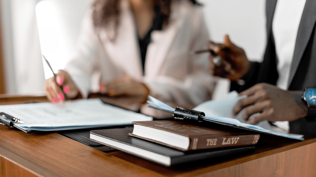 A lawyer holding a book and pen on a desk with a gavel in the background