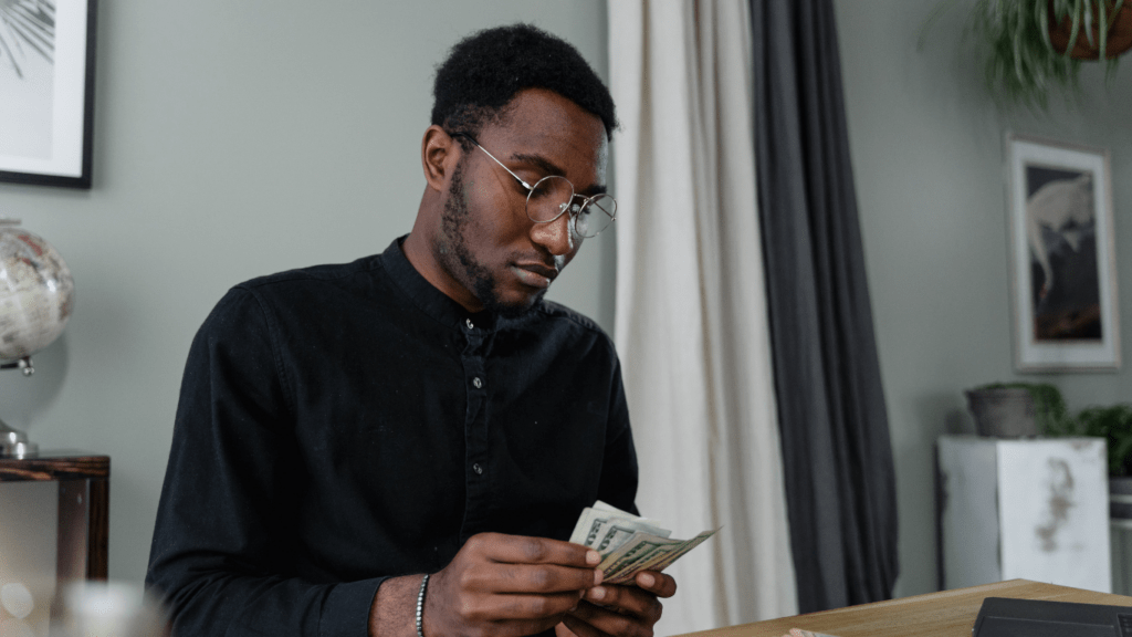 A person sitting in front of a laptop with money in their hand