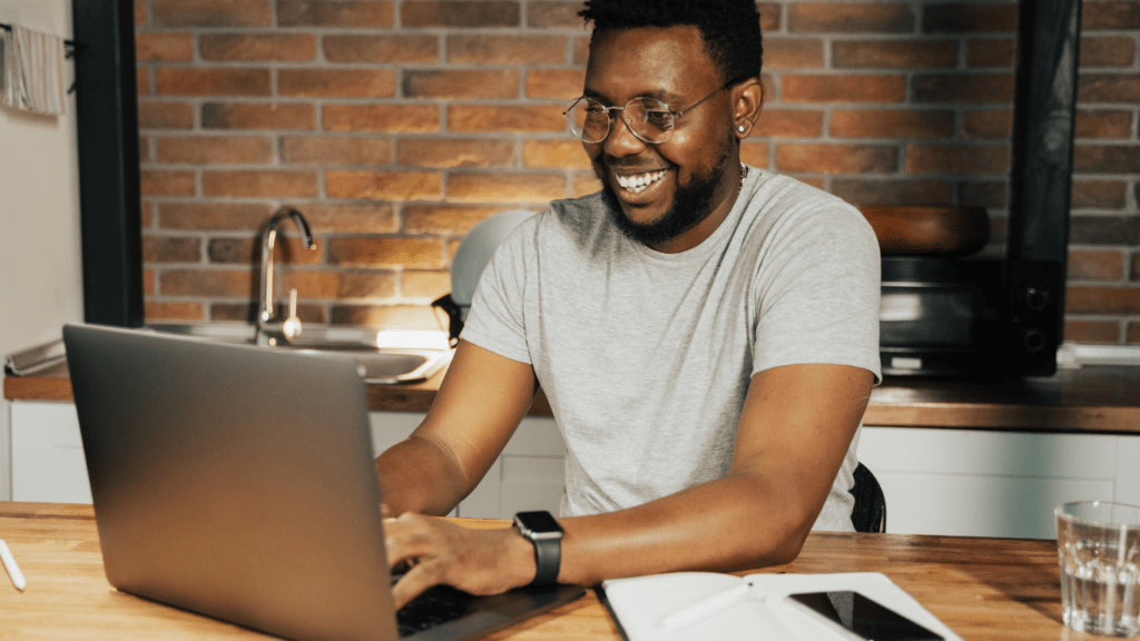 A smiling person working on a laptop