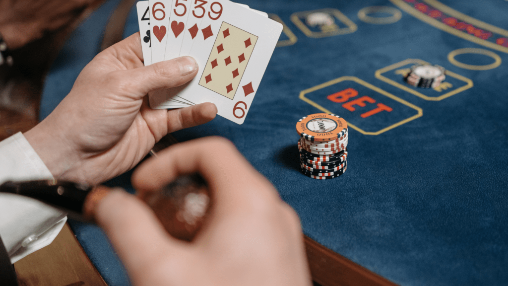 a person holding a pair of playing cards in front of a casino table