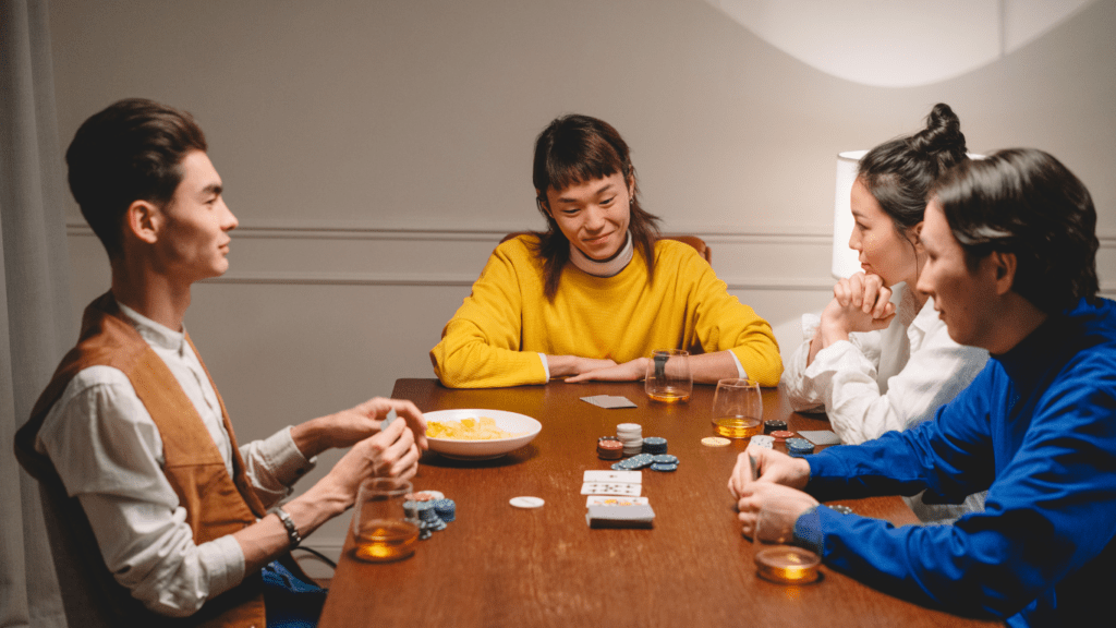 a group of people sitting around a table playing cards