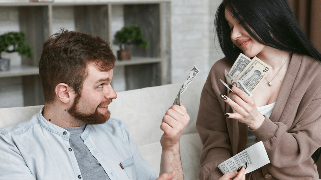 Two people sitting on a couch holding money