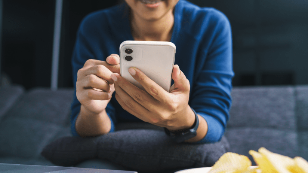 A person sitting on a couch holding a cell phone