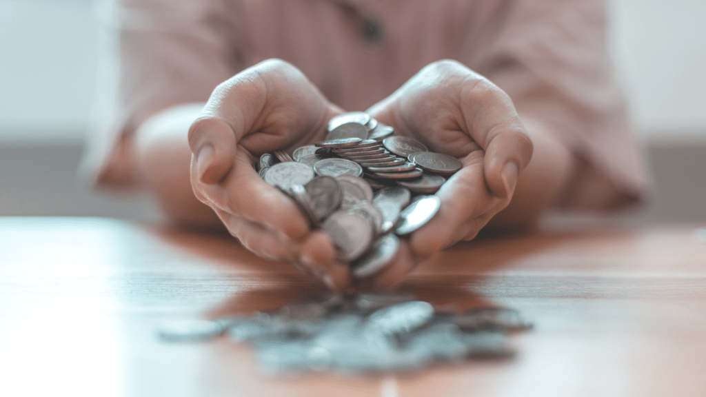 a person holding a pile of coins on a table