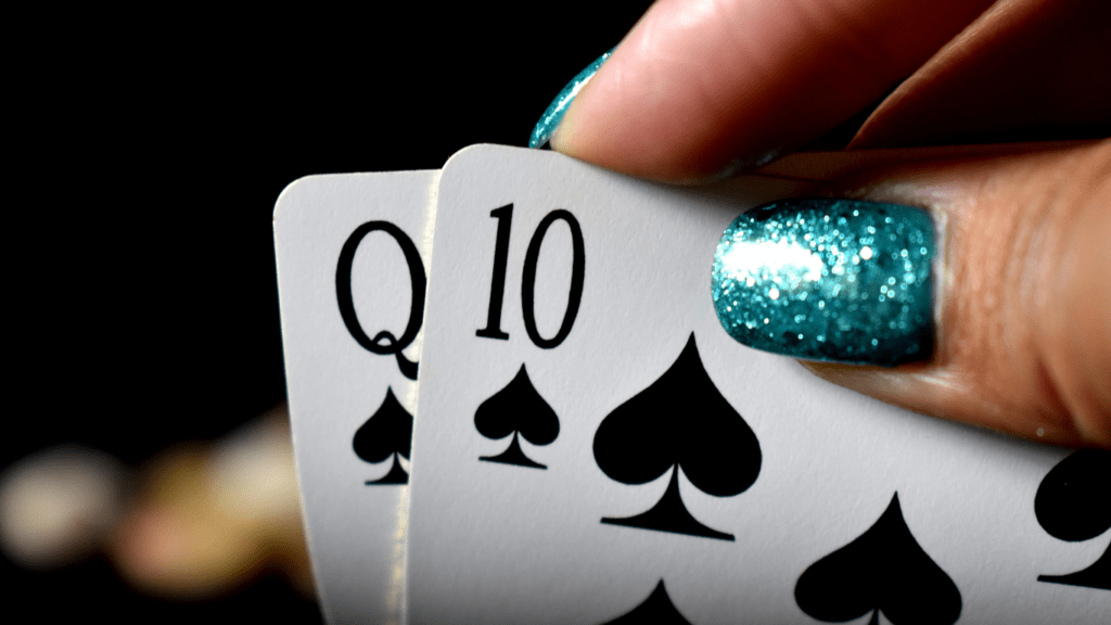 a person holding a pair of playing cards in front of a casino table