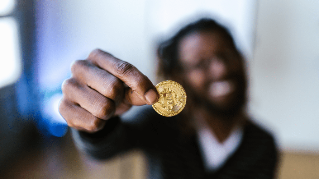 a person holding up a bitcoin in front of their face