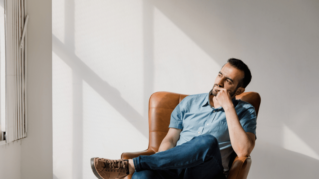 a person sitting in front of a window with their hand on their chin