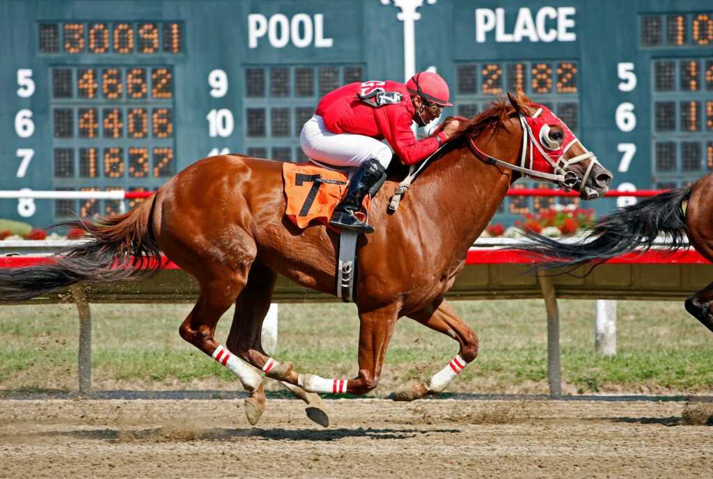 Dramatic horse racing scene with jockey in red competing fiercely on the track.